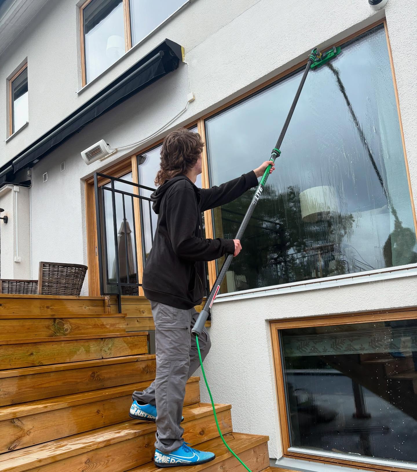 Tvättar fönster med renvattenfilter utvändigt på en villa